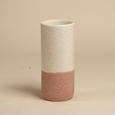 Die feey Keramik-Vase (Variado | 21 cm) hat eine gesprenkelte cremefarbene obere Hälfte und eine mattrosa untere Hälfte - perfekt als Blumenvase für Ihre Lieblingszimmerpflanzen. Steht aufrecht auf einer beigen Fläche vor einem einfarbig beigen Hintergrund.