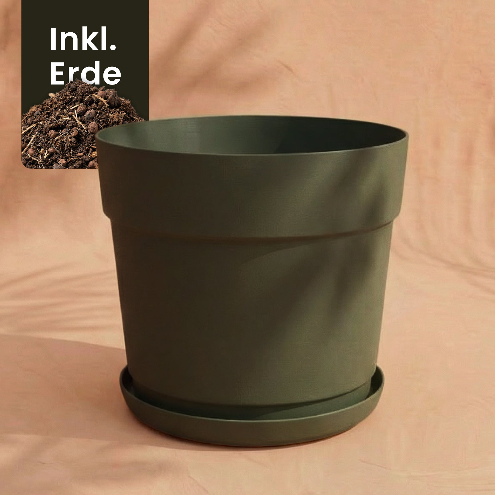 Ein großer, dunkelgrüner Kunststoff Pflanzkübel (Bloom | 29 cm Ø) aus recyceltem Kunststoff mit passender Untertasse steht auf einem pfirsichfarbenen Hintergrund. Oben links ist Erde aufgeschüttet, daneben steht 