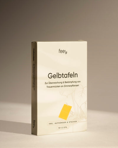 Eine Schachtel Feey Gelbtafeln zur Überwachung und Bekämpfung von Trauermücken und anderen Zimmerpflanzenschädlingen steht aufrecht vor einem neutralen beigen Hintergrund.