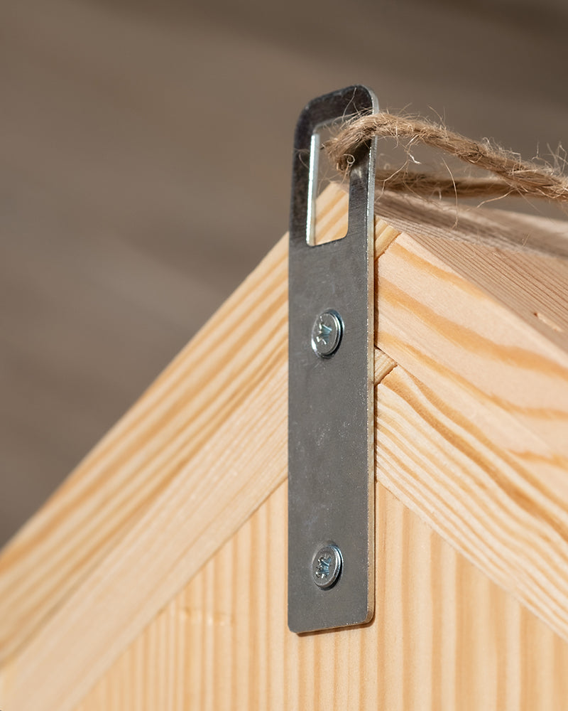 Nahaufnahme eines an der Wand befestigten Metallhakens, der in eine Holzoberfläche geschraubt ist. Ein Stück Schnur ist durch den Haken geschlungen, was darauf schließen lässt, dass er zum Aufhängen oder Befestigen von Gegenständen in Ihrem Garten verwendet werden könnte, vielleicht für ein Insektenhotel „Forsisens“, um Wildbienen anzulocken. Das Holz hat eine helle, natürliche Oberfläche mit sichtbaren Maserungen.