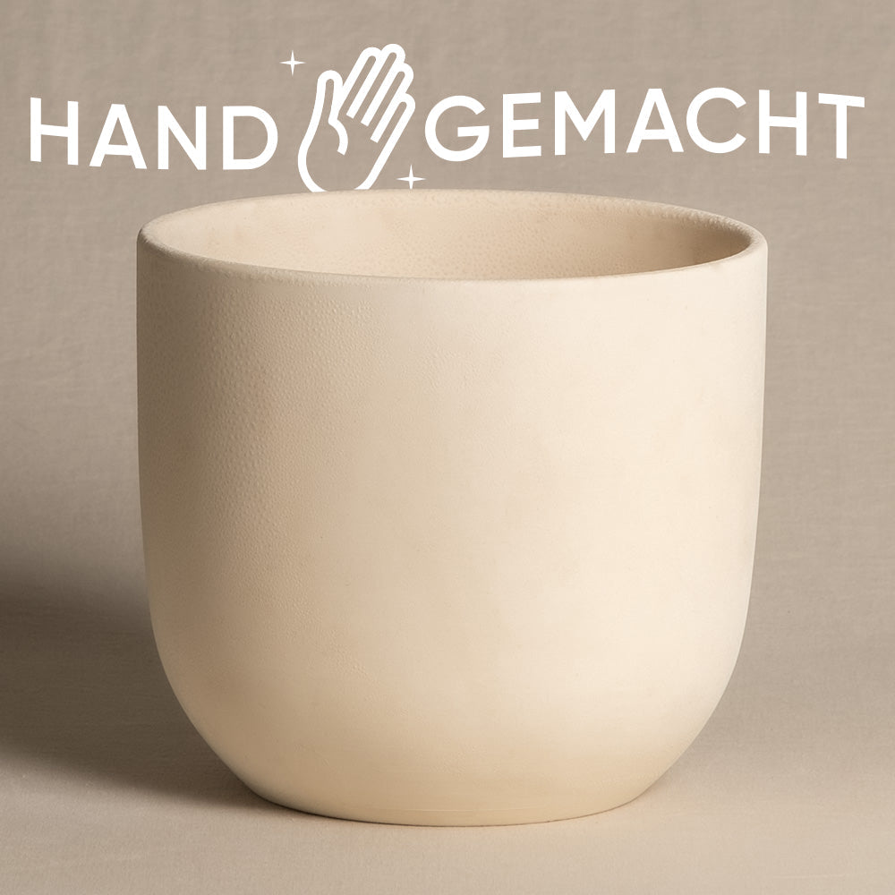 Ein glatter, cremeweißer, heller Keramik-Topf (Direito | 18 cm ⌀) steht zentriert auf einem beigen Untergrund. Oberhalb des Topfes ist ein stilisiertes Logo mit einer abgebildeten Hand und funkelndem Text „HAND GEMACHT“ zu sehen.