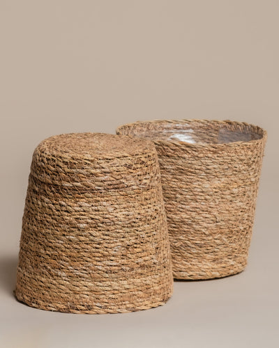 Das Pflanzkorb-Set aus Seegras (Kesat | 2× 18) ist auf neutralem Hintergrund arrangiert: Einer der Körbe steht offen, der andere ist umgedreht und präsentiert das natürliche Muster und die geflochtene Struktur.