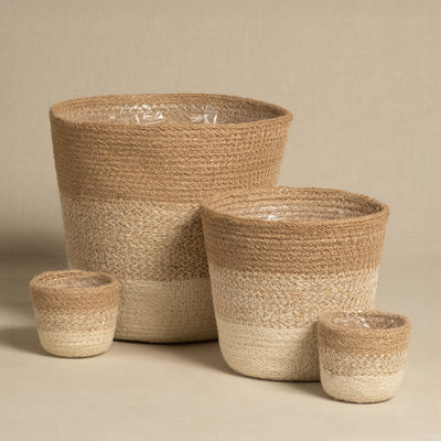 Das Pflanzenkorb-Set aus Jute (Lapis | 22, 16, 2×7) umfasst vier Körbe in verschiedenen Größen mit beige-cremefarbenem Colorblock-Design und transparenter Innenfolie, stilvoll auf neutralem Hintergrund arrangiert.