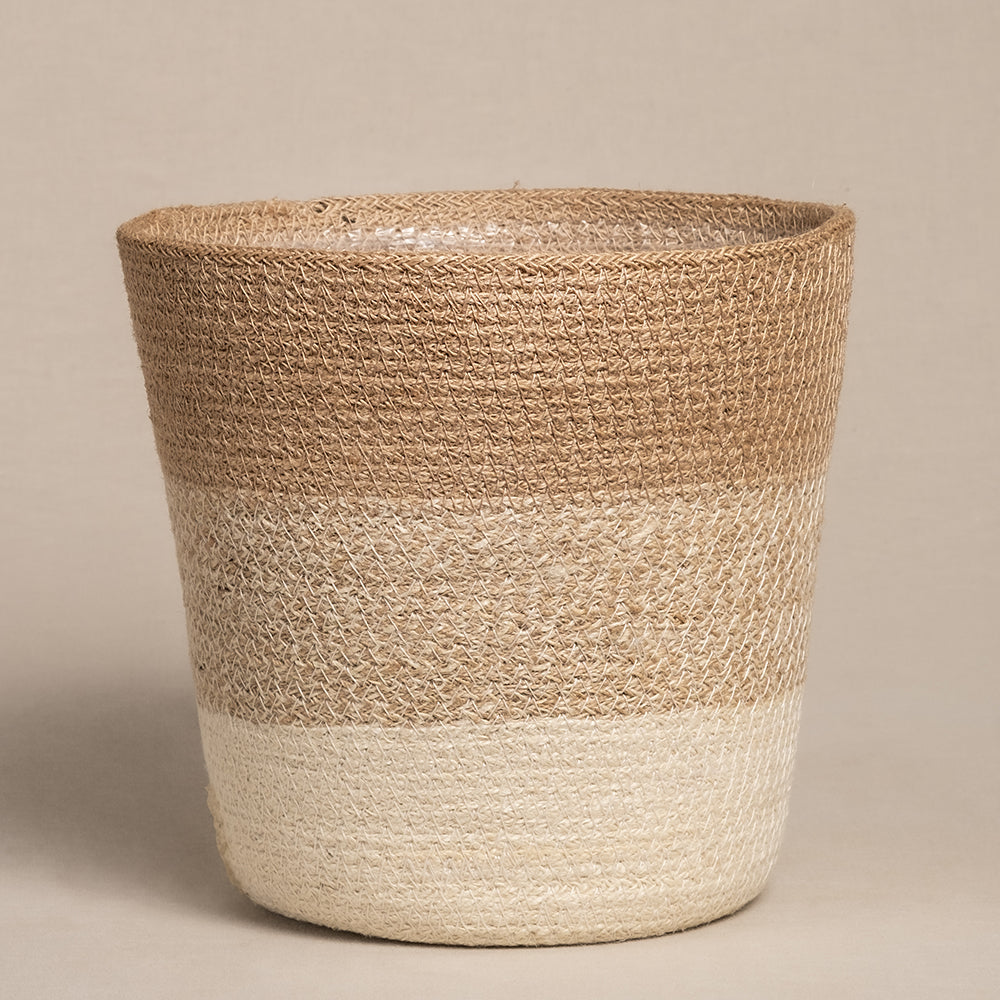 Der konisch zulaufende, geflochtene Pflanzenkorb aus Jute (Lapis | 22 cm Ø) verfügt über drei Bänder in Naturbraun bis Beige. Seine grobe Textur eignet sich perfekt, um Ihre Lieblingszimmerpflanze vor einem neutralen Hintergrund zu präsentieren.