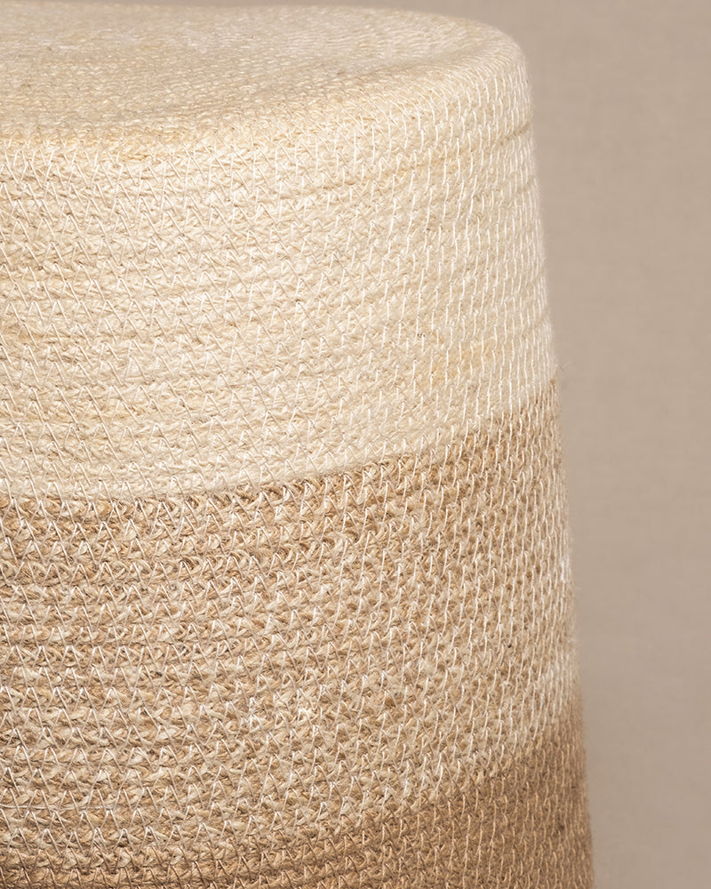 Nahaufnahme eines handgefertigten Pflanzkorbs aus Jute (Lapis | 30 cm Ø), der seine gewebte zylindrische Form mit horizontalen beigen und braunen Bändern zeigt. Die komplizierte Webstruktur hebt sich von einem schlichten Hintergrund ab.