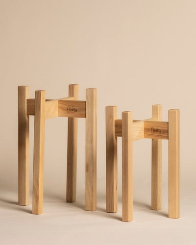 Zwei Pflanzenständer Duo (Stelion | 16, 14) mit minimalistischem Design und feey Gravur stehen in unterschiedlichen Höhen auf beigem Grund - ideal für stilvolle Zimmerpflanzen.