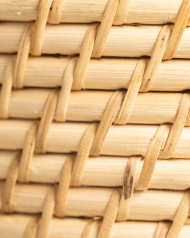 Nahaufnahme des Rattan-Babypflanzen-Korbs 'Calen' mit hellen, ineinander verschlungenen Rattanstreifen. Die Textur und das sich wiederholende Über-Unter-Flechtmuster sind deutlich erkennbar.