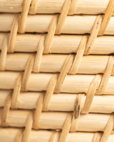 Nahaufnahme des Rattan-Babypflanzen-Korbs 'Calen' mit hellen, ineinander verschlungenen Rattanstreifen. Die Textur und das sich wiederholende Über-Unter-Flechtmuster sind deutlich erkennbar.
