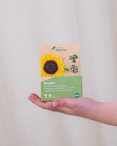 RhizoSan Verpackung wird von einer Hand von rechts ins Bild gehalten.