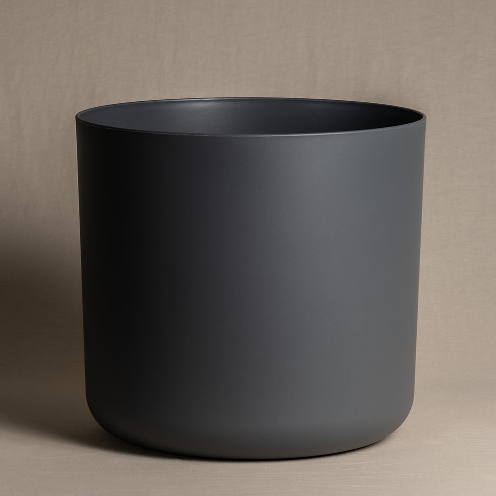 Ein minimalistischer, mattschwarzer Kunststoff-Topf (Soft | 35 cm ⌀) mit glatten Oberflächen wird vor einem neutralen beigen Hintergrund präsentiert. Der Topf hat keine sichtbaren Verzierungen oder Griffe, was sein klares und modernes Design unterstreicht und gleichzeitig recycelbar ist.