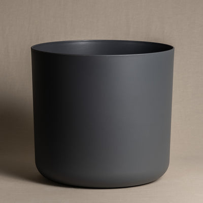Ein minimalistischer, mattschwarzer Kunststoff-Topf (Soft | 35 cm ⌀) mit glatten Oberflächen wird vor einem neutralen beigen Hintergrund präsentiert. Der Topf hat keine sichtbaren Verzierungen oder Griffe, was sein klares und modernes Design unterstreicht und gleichzeitig recycelbar ist.