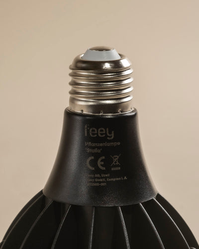 Nahaufnahme einer schwarzen LED-Pflanzenlampe mit metallischem Schraubsockel, die Produktdetails und die Zertifizierung auf dem Hals zeigt. Sie wurde entwickelt, um das Sonnenlicht für ein gesundes Wachstum von Zimmerpflanzen zu imitieren, und steht vor einem neutralen beigen Hintergrund.
