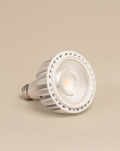 Eine weiße Pflanzenlampe mit metallischem Schraubsockel ruht auf der Seite vor einem beigen Hintergrund. Mit ihrer strukturierten Linse und dem belüfteten Kühlkörper ist sie perfekt für die Versorgung von Zimmerpflanzen mit Sonnenlicht geeignet.