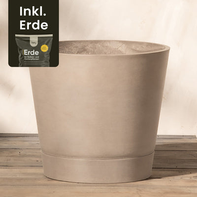 Ein großer, beiger Kunststoff-Pflanzkübel (Venedig | 30 cm ⌀) steht auf einer Holzfläche vor hellem Hintergrund. In der oberen linken Ecke ist ein kleines Bild eines Sacks Erde mit dem Text „Inkl. Erde“ zu sehen, was darauf hinweist, dass die Erde im Lieferumfang enthalten ist. Dieser Pflanzkübel aus Recycling-Kunststoff sorgt für Langlebigkeit und Nachhaltigkeit.