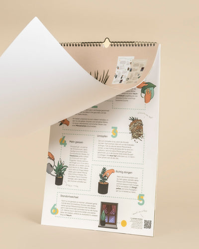 Der Pflanzenkalender ist ein spiralgebundener, immerwährender Kalender in deutscher Sprache mit illustrierten Pflegetipps für Zimmerpflanzen. Er zeigt Zeichnungen von Pflanzen, Töpfen und Händen auf einem beigen Hintergrund, wobei eine Seite teilweise umgeschlagen wird, um die nächste zu zeigen.