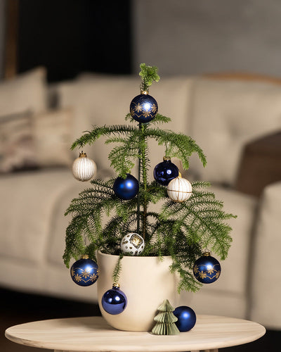 Wohnzimmeraufnahme von Weihnachtsbaum im Topf. Geschmückt mit Weihnachtskugeln