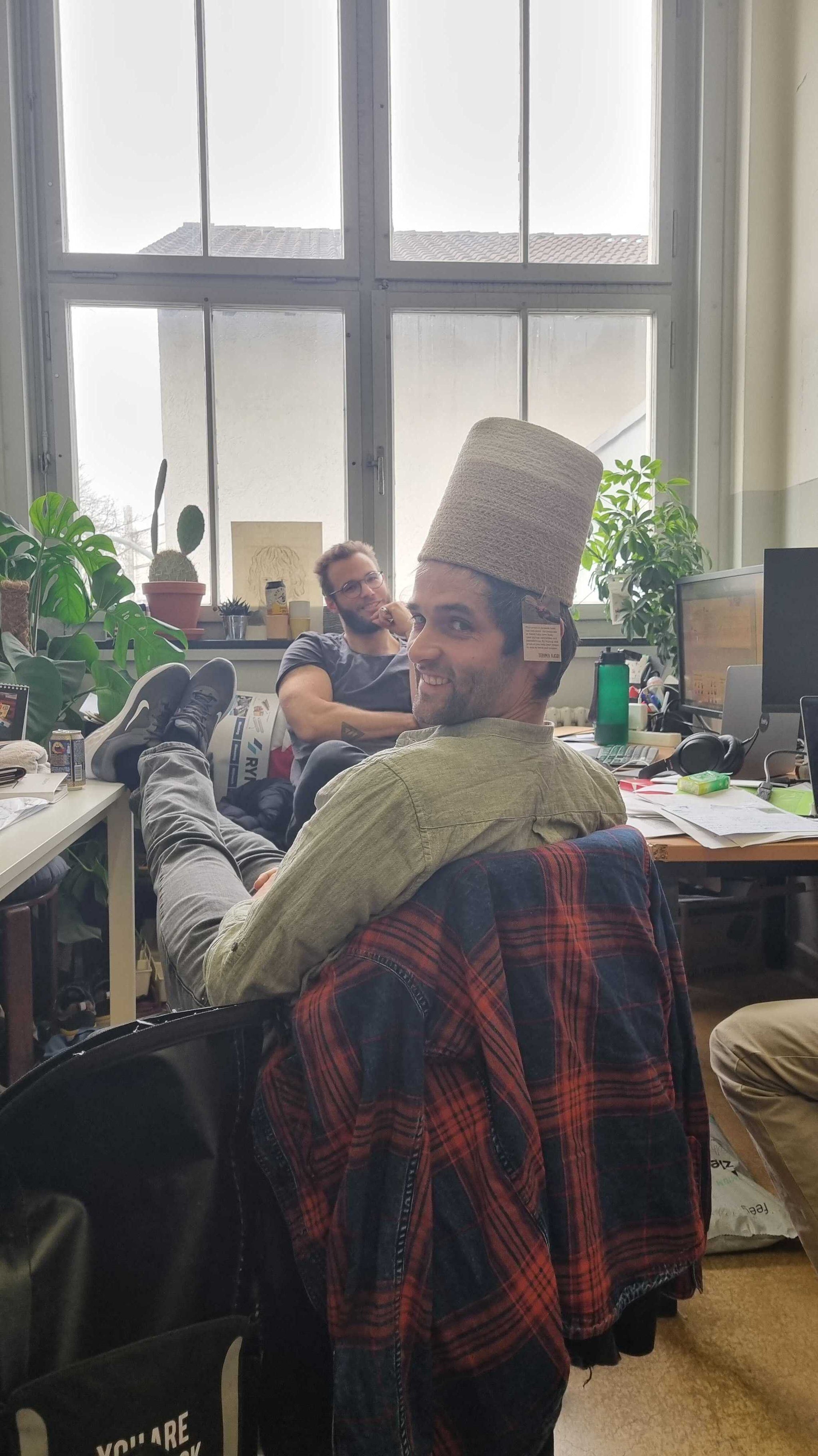 Ein Mann trägt in einem Büro einen geflochten Pflanzenkorb aus Seegras auf dem Topf.